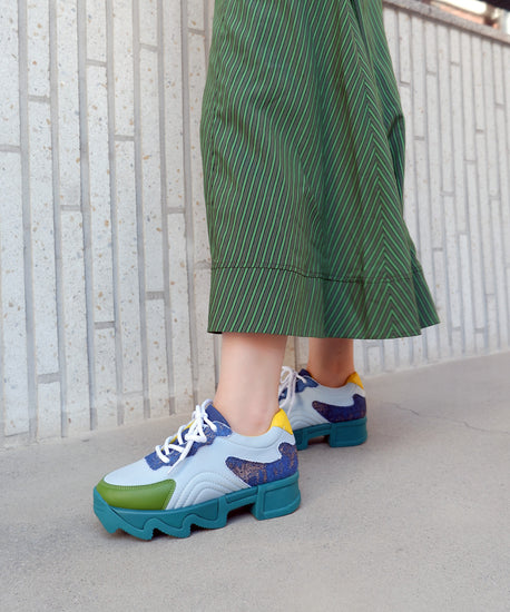 A person wearing ERB multi colored lace-up sneaker with iRi outsole, walking around the park showing the comfort of the sneakers